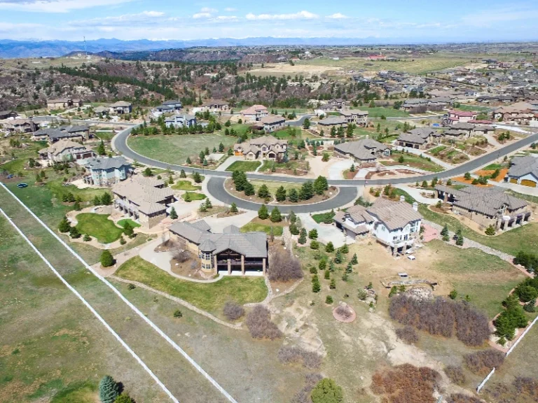 Aerial view of a suburban neighborhood with large houses, curved roads, and open grassy areas. water damage restoration in Castle Rock CO