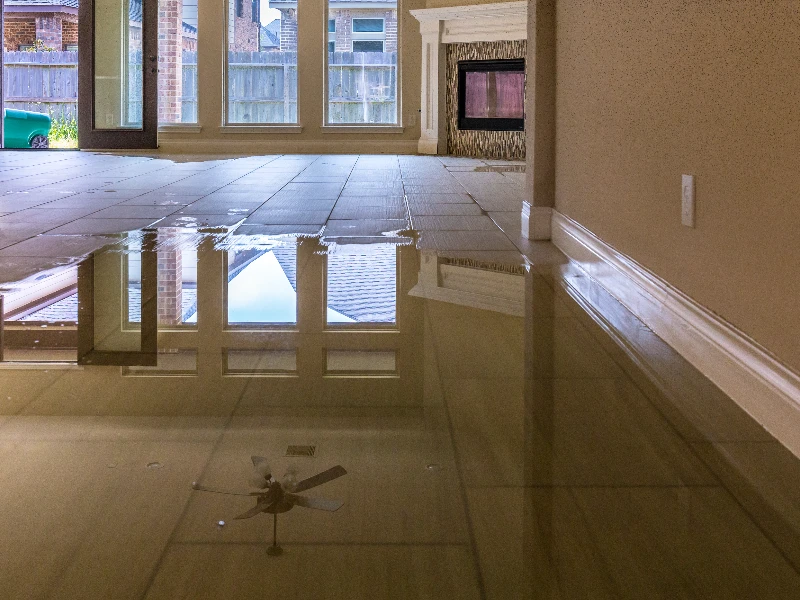 Water flooding a tiled floor inside a room with large windows and a fireplace. certified restoration company