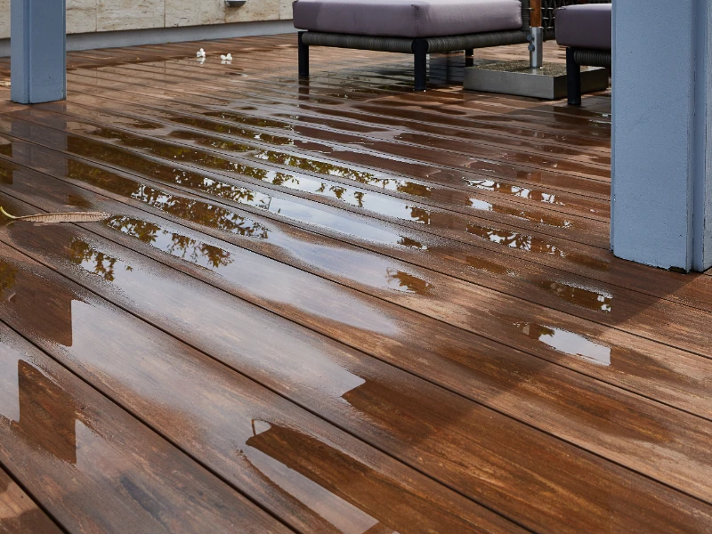 Wet wooden deck with reflections and outdoor furniture legs visible. water damage restoration